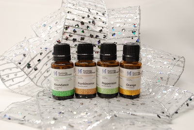 New Year Goals Essential Oils Bundle on table with sliver ribbon: Abundance, Frankincense, Peppermint, Orange