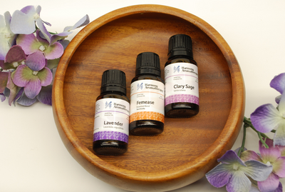 wood bowl with three oils, lavender, femease and clary sage bottles laying in the middle