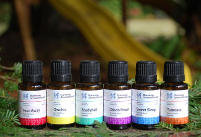 six kid friendly essential oils on table w/ greenery : Fear Away, Owchie, Studyhall, Disco Power, Sweet Sleep & Tumease